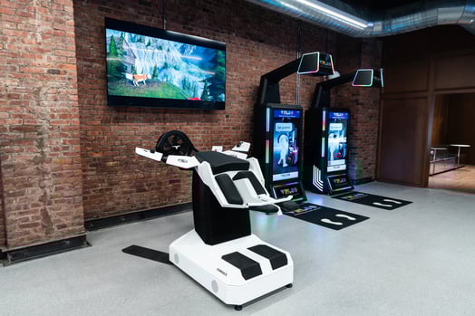 A VR device where the user lies down and experiences what it might be like to fly next to two VR arcade machines.