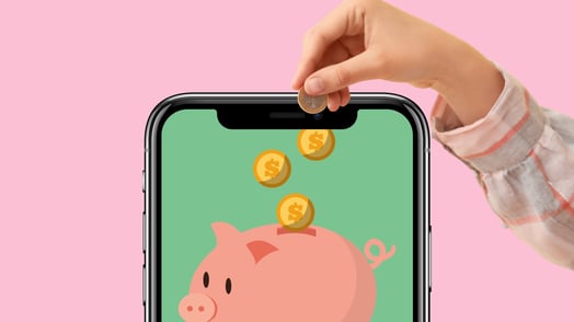 A child’s hand putting a coin into a piggy bank displayed on a smartphone screen.