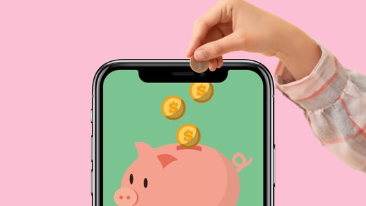 A child’s hand putting a coin into a piggy bank displayed on a smartphone screen. 