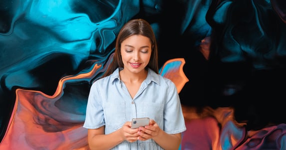 A woman in a blue shirt taps on her phone.