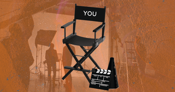 A director’s chair with “YOU” written on it and a film set in the background. 