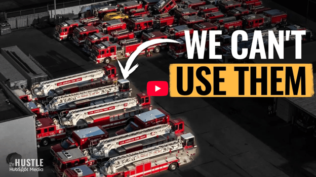 An aerial view of numerous red and white fire trucks parked in a lot, with large overlay text reading "WE CAN'T USE THEM."
