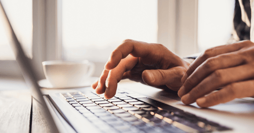 Hands typing on a laptop keyboard.