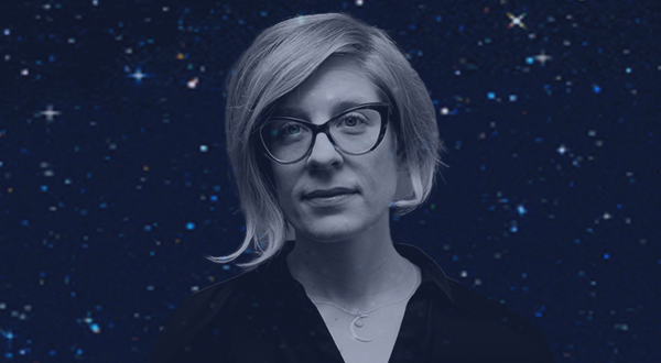 A portrait of Kathryn Nicolai, a woman with short blonde hair and cat-eye glasses, set against a dark, starry background.